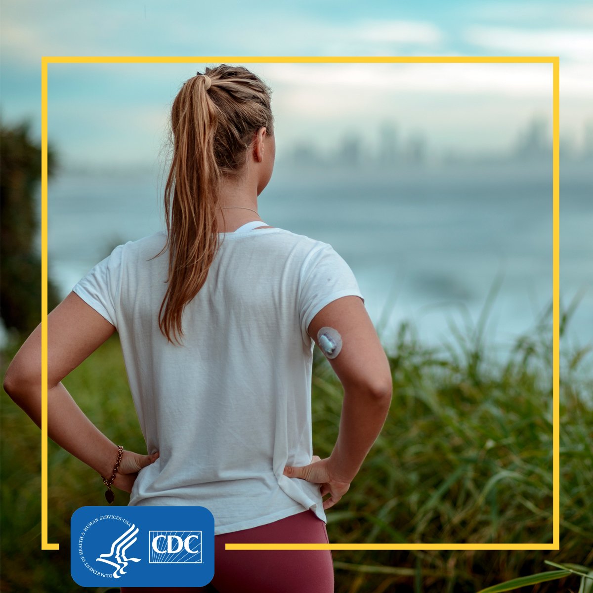 A woman looking out over the coast, with an insulin pump on her arm.