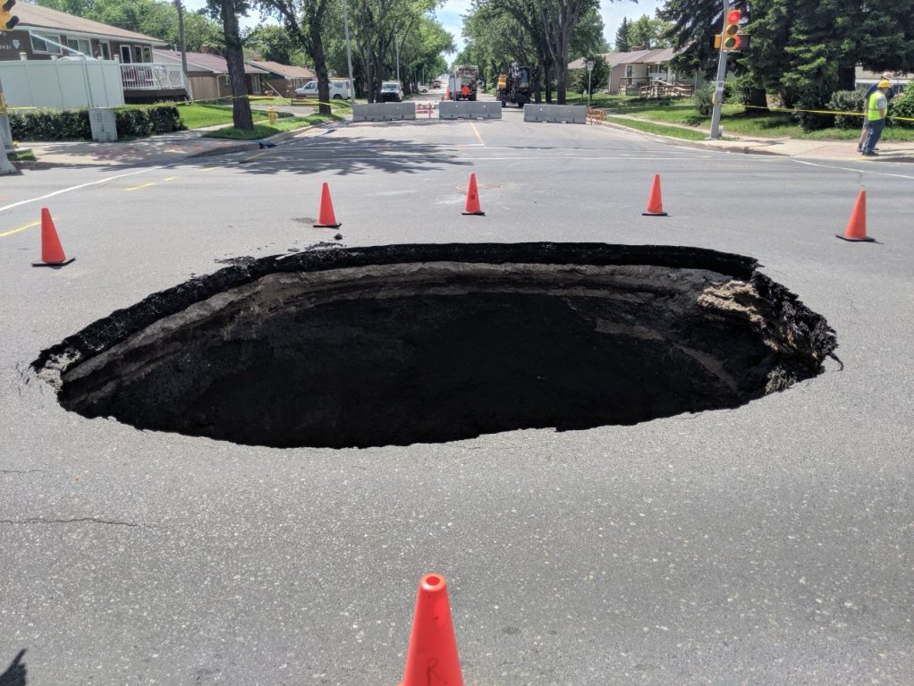 reginapolice's tweet photo. The sink hole at Avonhurst Dr and Elphinstone is not a new swimming pool; do not try to climb inside or go near it. The ground around is unstable and may give. Make your safety a priority. @CityofRegina https://t.co/QbqIqCI50o