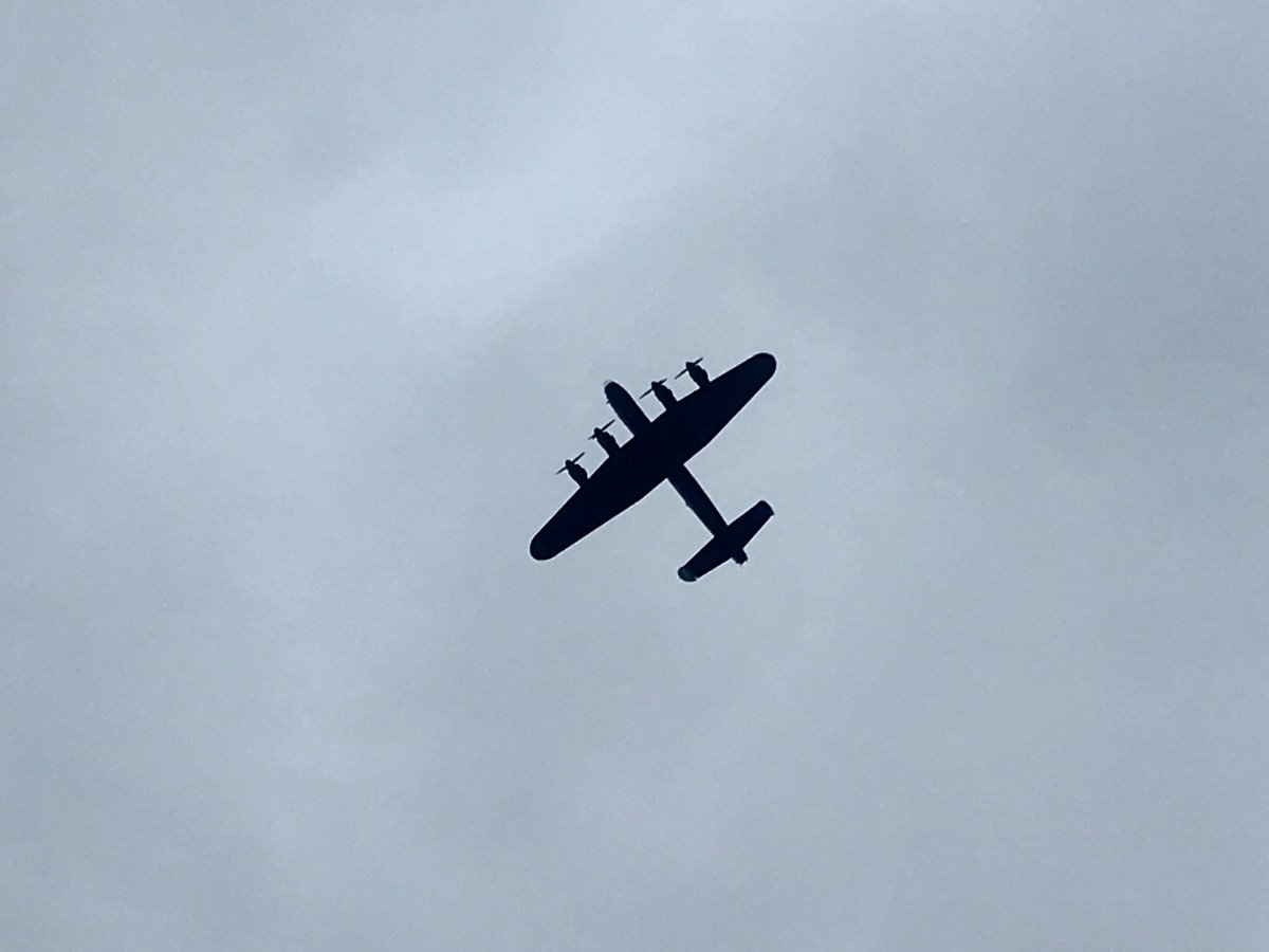 A grey sky with a black silhouette of a four-engined plane.
