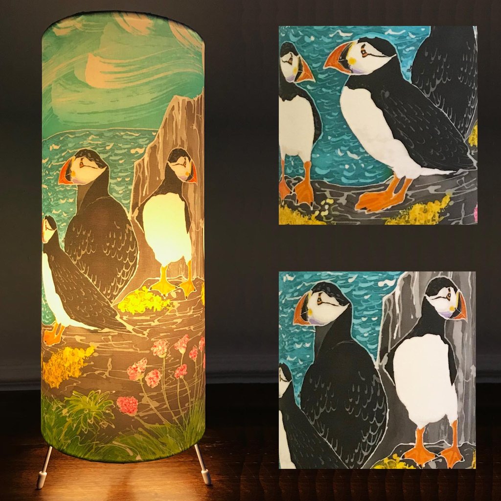 king_therese's tweet photo. Elegant cylindrical table lamp featuring a group of cheeky black white and orange clowns who are happily standing together on a Lichen covered rock, with a splashy sea and swirly sky overhead on Skomer Island. From an original batik painting #puffin #atlanticpuffin https://t.co/nLDfZUZQBF