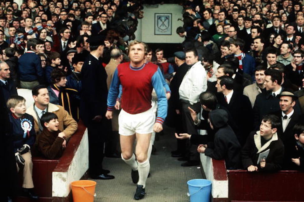 boleynbadges's tweet photo. Football, London, 1970, West Ham captain Bobby Moore leads out his team before a game at Upton Park as the crowd watches https://t.co/Mn4br5qs8w