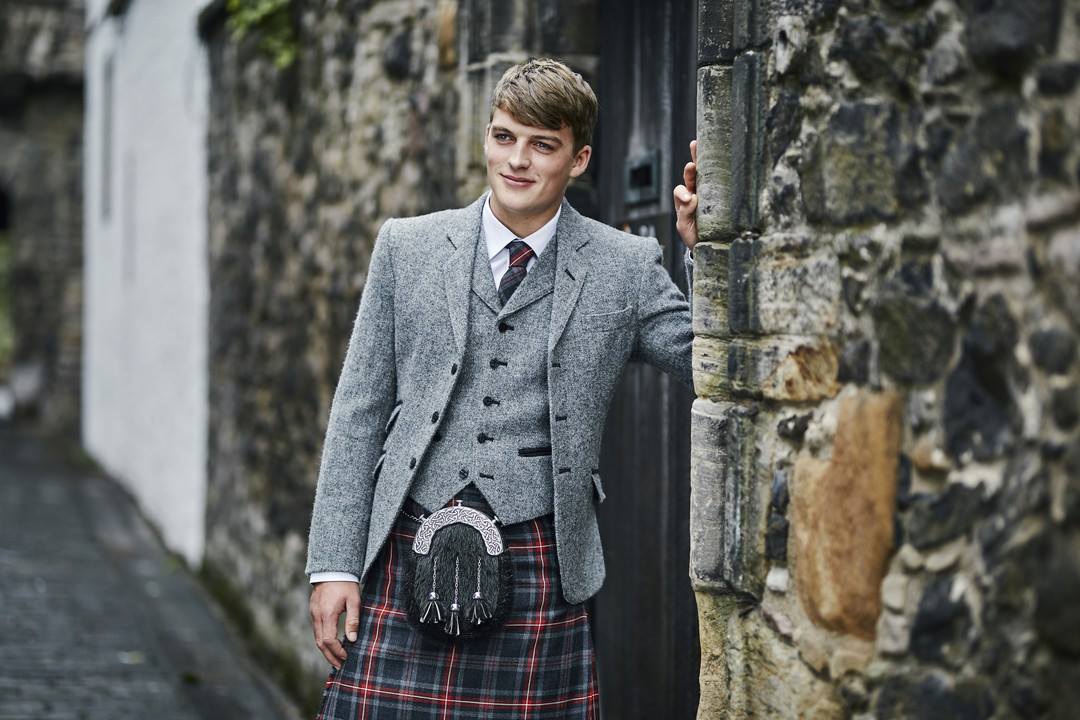 Eight Yards on X Quality kilts made in Scotland. Martin models our exclusive Hebridean Fire tartan kilt Victorian charcoal sporran and the K2 light grey Harris Tweed jacket and waistcoat. A perfect