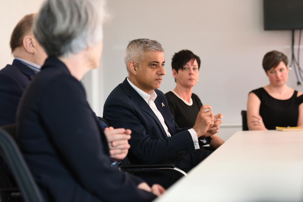 Five people, three women and two men, sit on one side of the conference room table, listening with thoughtful expressions.