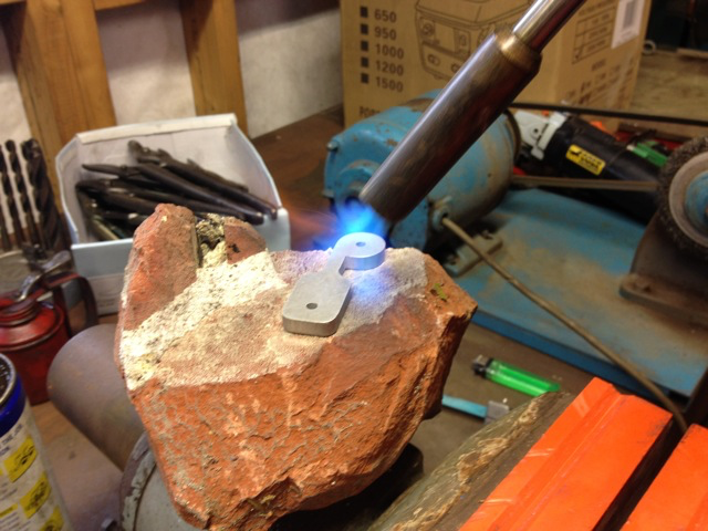 From the archives of Bomo's Backyard Manufacturing. Blowtorching the first hundred Mr. Tappies on an old brick in order to put the 90 degree twist in the 5083 alloy.