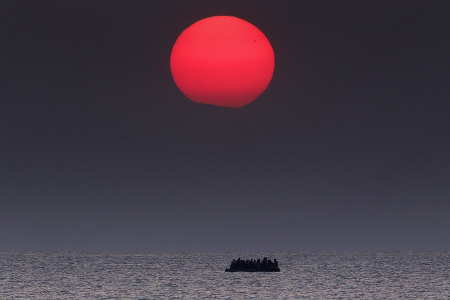 Photo by Yannis Behrakis: A boat with refugees in the sea, at sunset. Reuters.