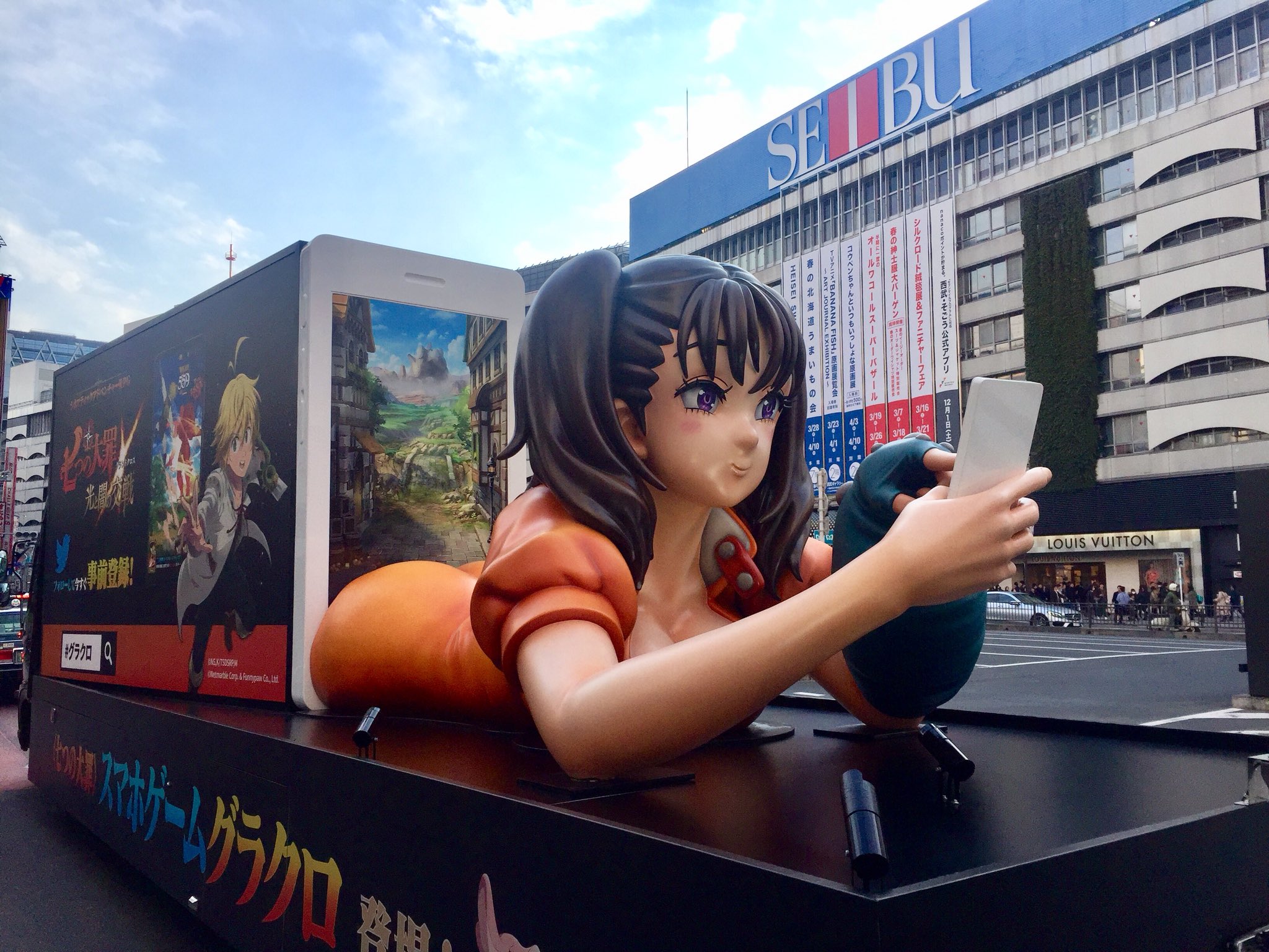 痛車天国 池袋で 七つの大罪 スマホゲームアプリのアドトラックに遭遇 荷台部分にはスマホゲームに興じる巨大なディアンヌが これも痛車 なのか 巨大な立体像を牽引トレーラーに載せて引っ張るというアイデアはありそうですね 立体痛車の