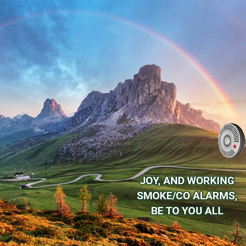 A smoke alarm at the end of a rainbow. The text reads: Joy and working smoke alarms be to you all.