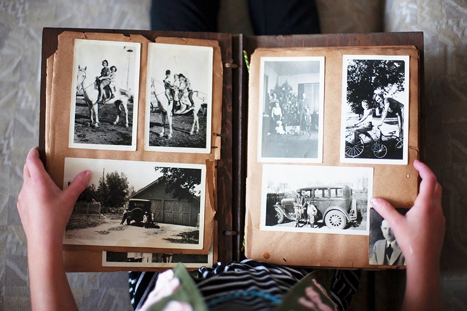 a woman holding an old vitange style photo album open on her lap