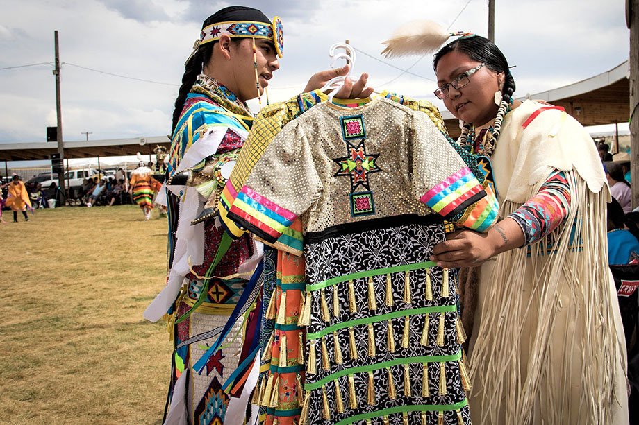 two Native American people looking over traditional dress at a pow wow