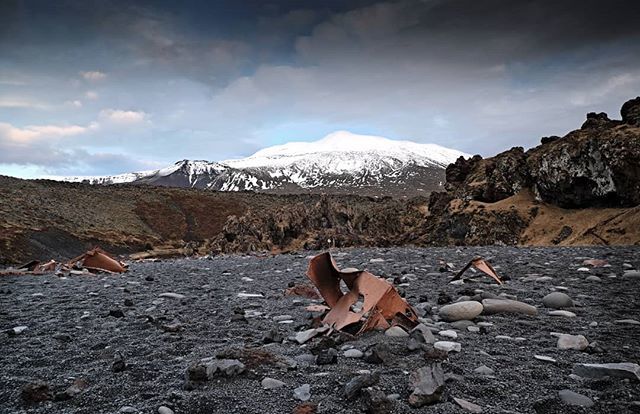 4cornersfoto's tweet photo. Djupallonssandur (Black Lava Pearl Beach) in Iceland with the Snaefellsjokull glacier in the background. The pieces of metal you can see are from the shipwrecked British trawler The Epine GY7 which sunk in 1948 with the loss of fourteen lives... https://t.co/N5vXVVQDo7