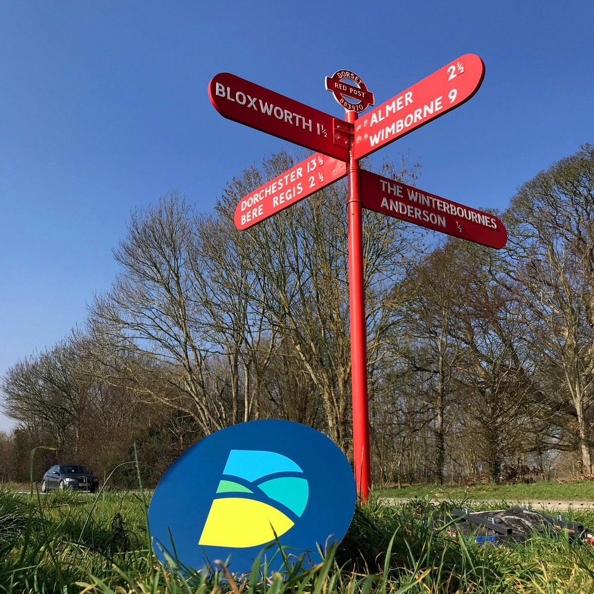 DorsetCouncilUK's tweet photo. Among the thousands of standard white signs scattered throughout Dorset are just three of these ‘red posts’. This well restored example is near Bloxworth on the A31. Why are they red? It's a bit of a mystery. Do you know where the other two are located? #workingfordorset https://t.co/pxHHZ24xJL