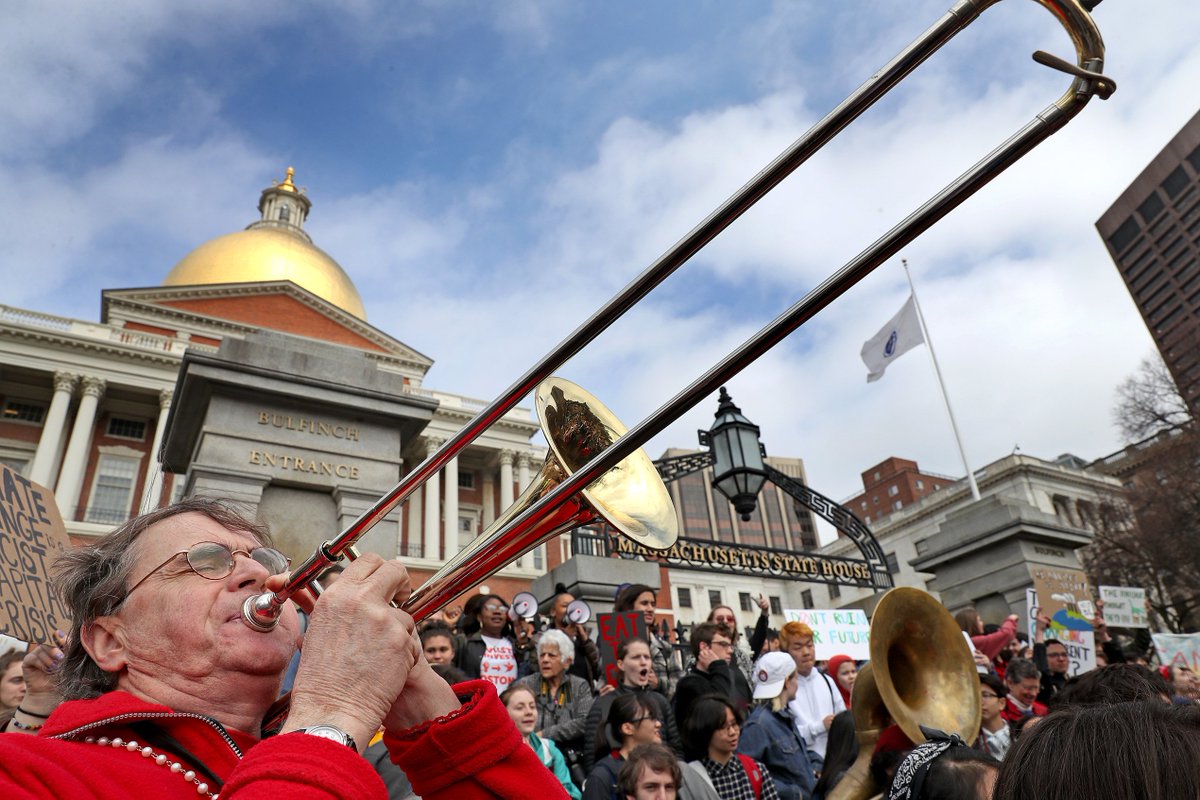 Tooting his horn is John Bell with the Second Line Social Aid &amp; Pleasure Society Brass Band with hundreds of students rally in front of the State House Friday afternon as students worldwide skip class to demand action of climate