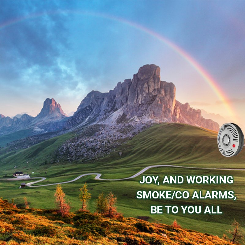 A mountain with a rainbow streaking across the sky. A smoke alarm at the end. The text reads: Joy, and working smoke alarms be to you all.