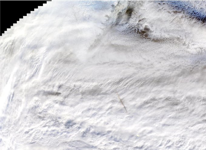 Satellite image of a meteor’s shadow, visible as a gray streak in the lower center, above white clouds