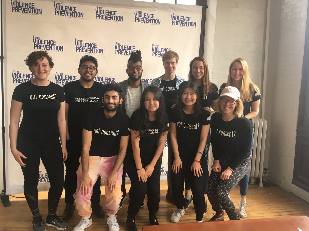 A group of 10 students and staff at Penn wearing black shirts that say "Got Consent?" on them in front of a banner that says "Penn Violence Prevention."