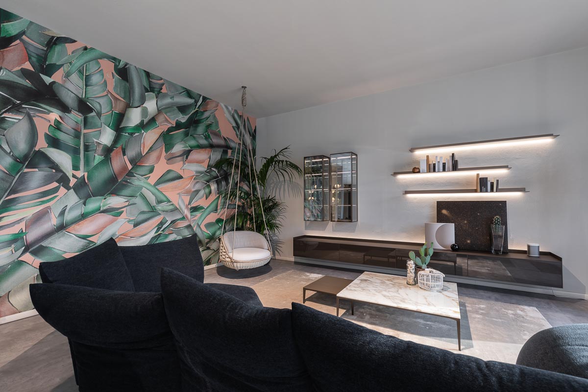 Lo showroom, posto ideale per sperimentare e inserire il tocco inaspettato. 
Un’atmosfera sobria se non fosse per le grandi foglie verdi su rosa pastello... Lo definiamo un soggiorno elegante, dal tocco ironico.