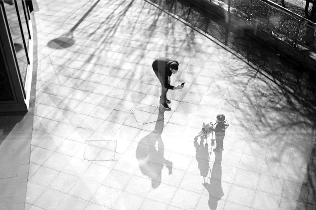 Street photography can catch some simple yet beautiful moments like this one of a dad taking a picture of his child with their pram #streetphotographer #streetphotographers #streetlevelphotography #streetphotobnw #daddyslove #childsplay