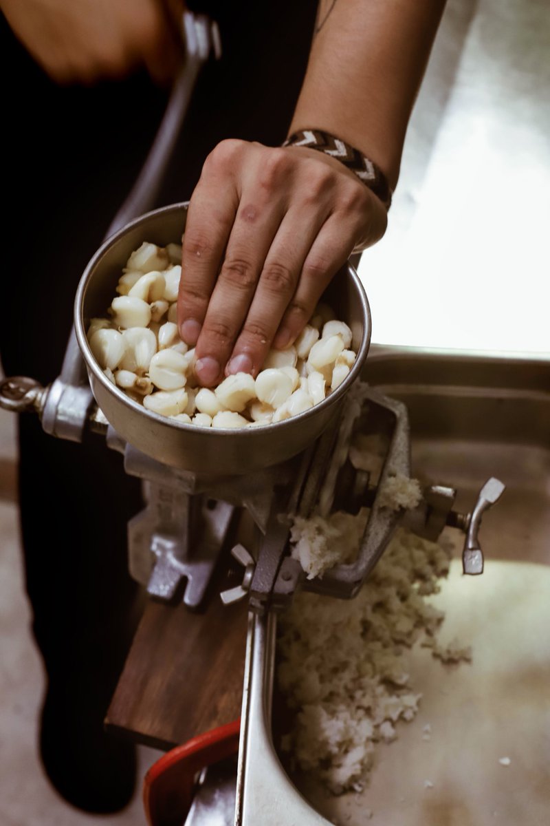 ¡Moliendo maíz! Para preparar nuestras arepas, lavamos el maíz blanco dos veces antes de cocinar para remover el almidón. Luego, en una olla con abundante agua agregamos sal y azúcar y revolvemos para evitar que se pegue. Cocinamos a fuego alto hasta que el maíz esté blando.