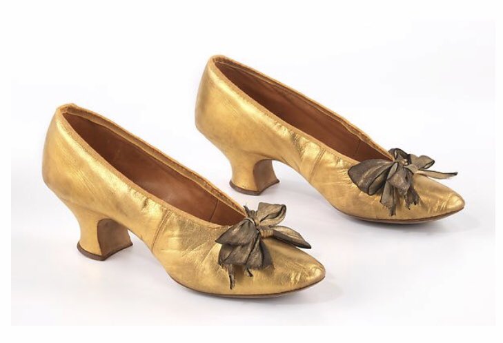 Golden like the sun which has appeared to have arrived, these 1900 evening shoes have been made from a metallic leather, unusual for the time. The use of this was not widespread until the 1920’s. Two gold lamé ribbon bows finish the deal in creating beautiful shoes. <a href="/metmuseum/">The Metropolitan Museum of Art</a>