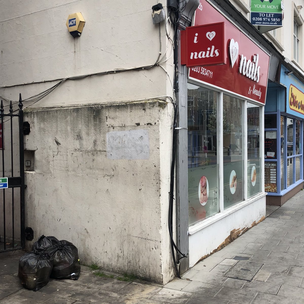 On closer inspection, it’s a thick layer of concrete, either up against or cutting through the wall of the presumably brick building. This shop has been armoured...