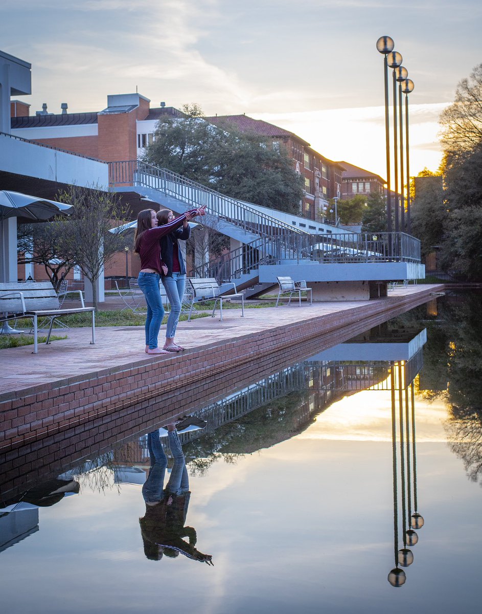 kenscar1's tweet photo. My daughter and her BFF enjoying a lovely sunset on the @ClemsonUniv campus #Sunset #reflections #water #mirror #Clemson #architecture #architecturephotography https://t.co/aS2zbNLXWa