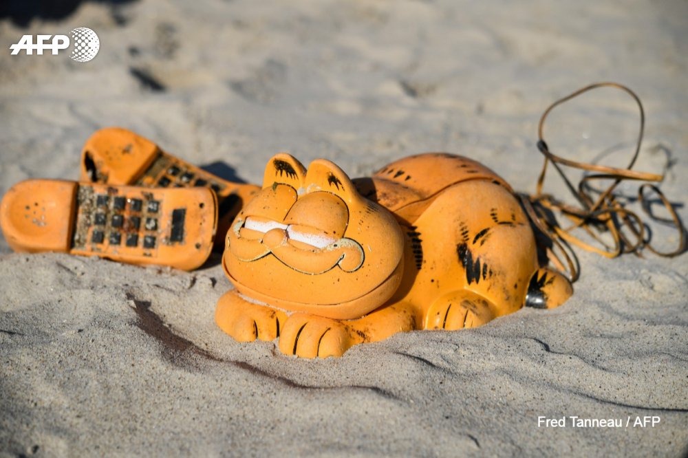 Depuis plus de 30 ans, des téléphones en plastique orange à l'effigie du chat Garfield s'échouent sur les plages bretonnes. Le mystère vient d'être en partie levé avec la découverte d'un conteneur échoué dans une faille du littoral nord-finistérien u.afp.com/Jqt9 #AFP