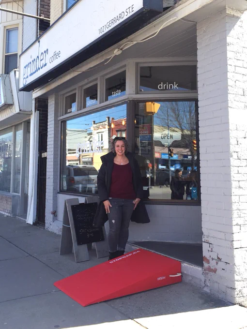 Joelle Murray smiles outside of Grinder Coffee with their new red StopGap ramp. 