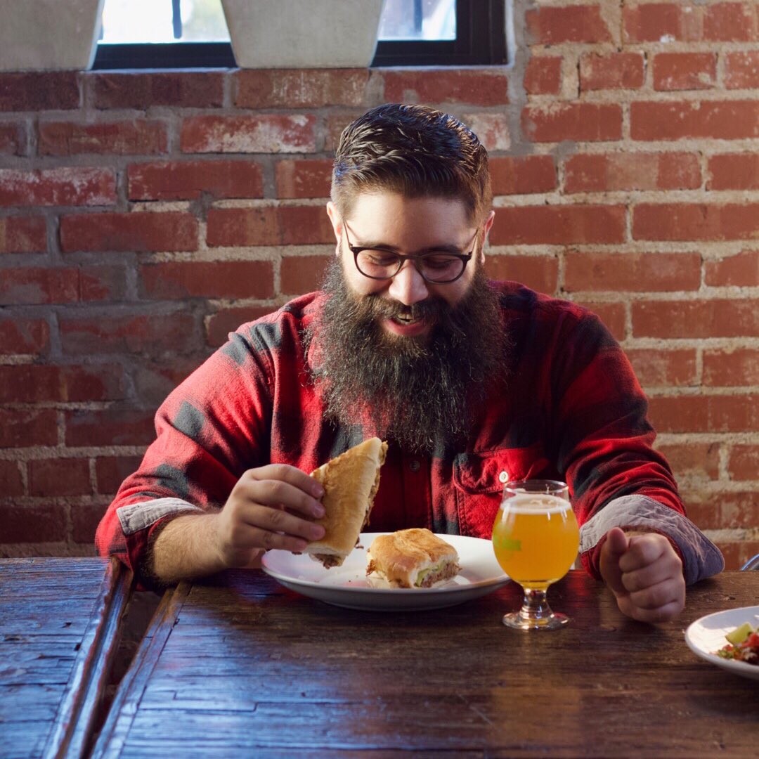 Happy mature bald bearded hipster man drinking coffee while working overtime