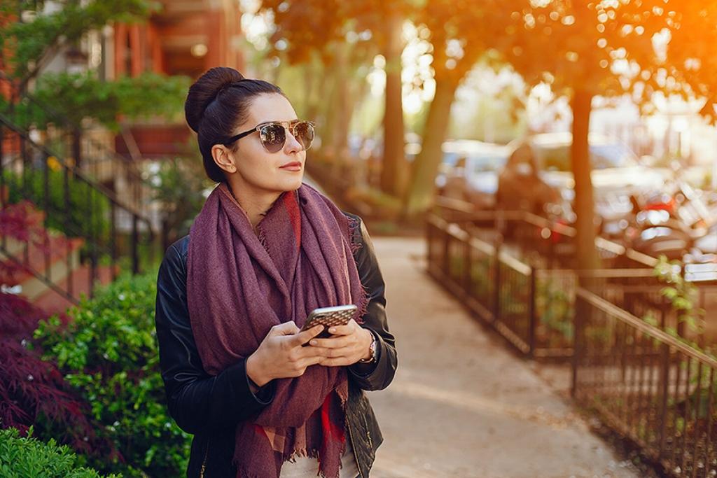 Woman using a smartphone in an urban neighborhood.