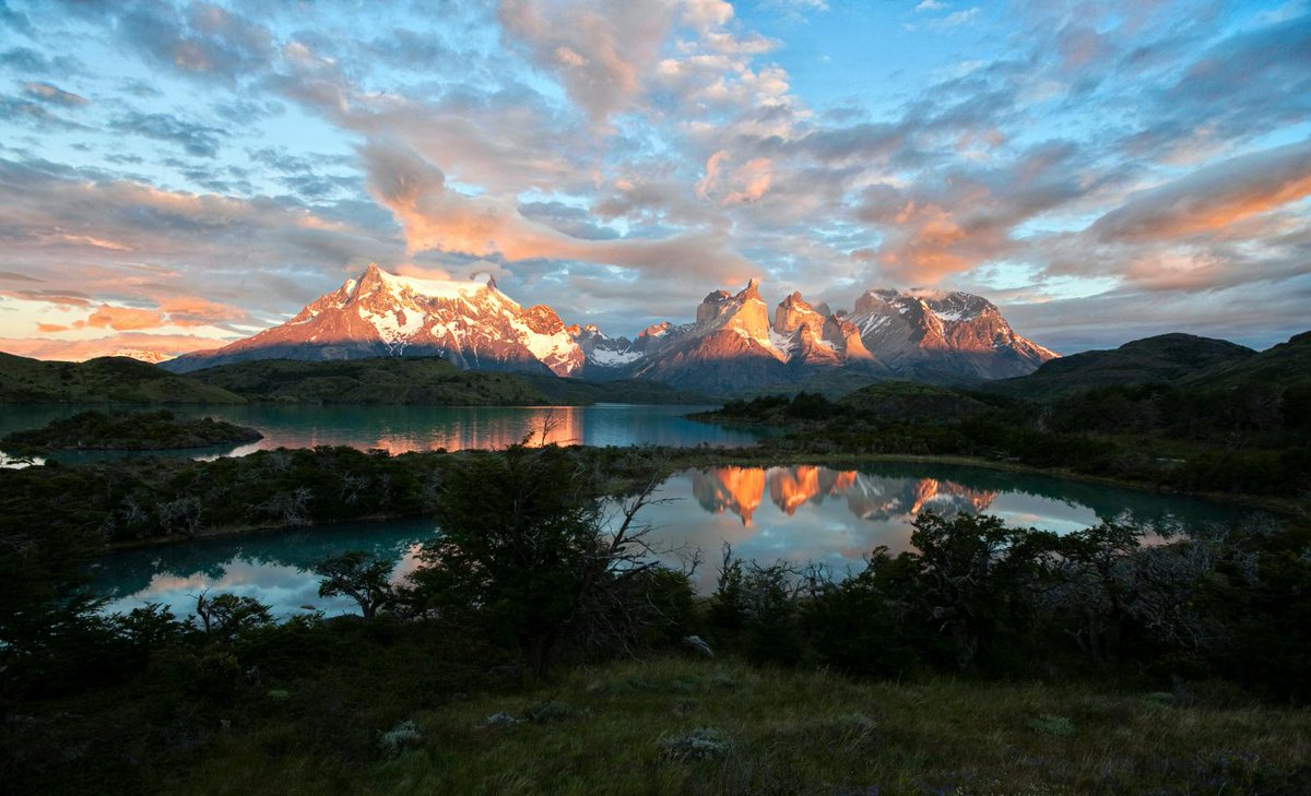 blue skies with clouds, sunlit mountain tops, forest and river