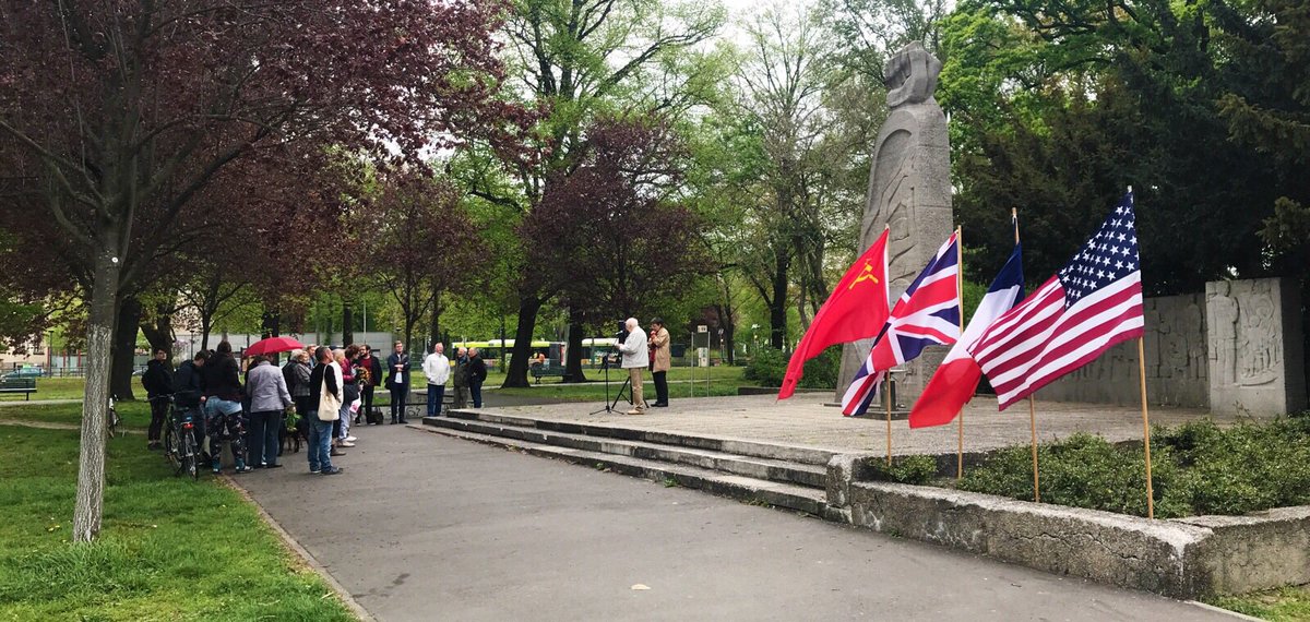 Der Platz des 23 April 2019, rechts im Bild die Fahnen der Vereinten Nationen, also USA, Frankreich, Großbritannien, Sovietunion, links einen gruppe von Menschen.