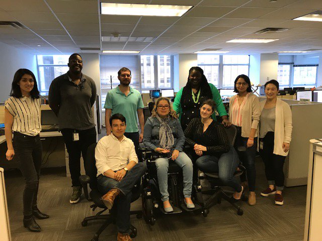 The image shows nine people standing and sitting together, wearing denim.