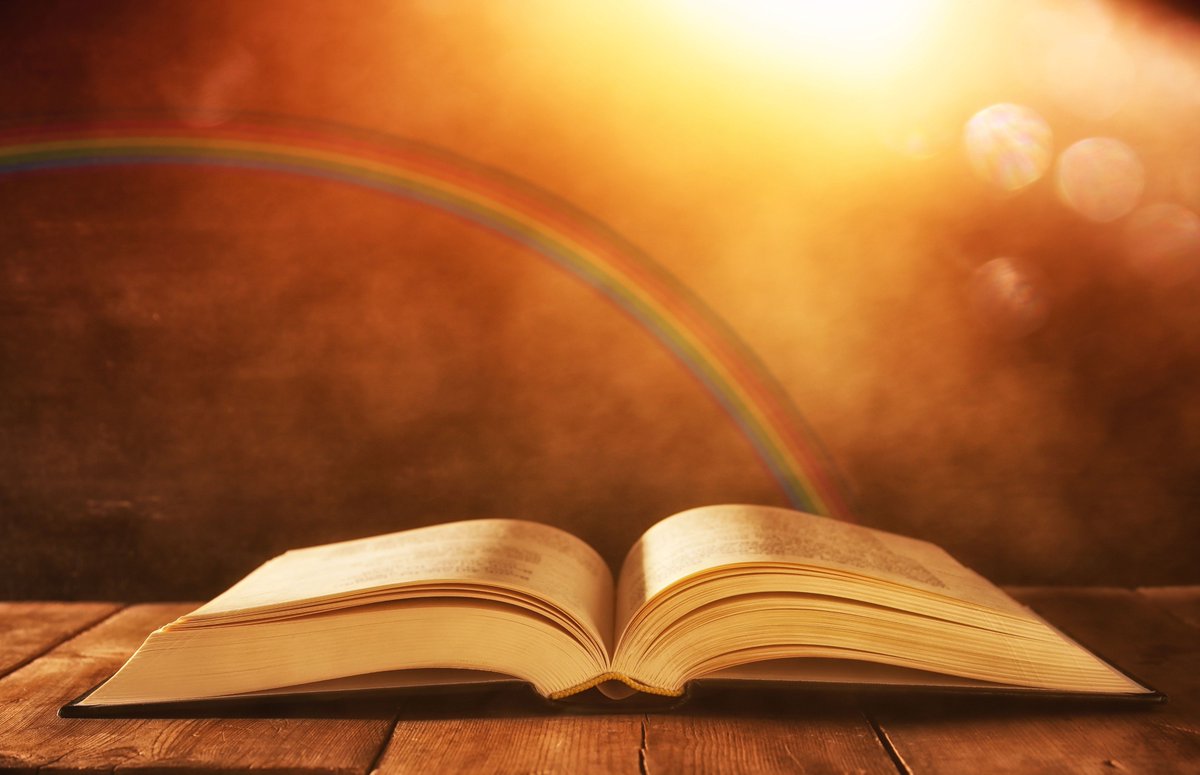 Bible laying on table with rainbow behind