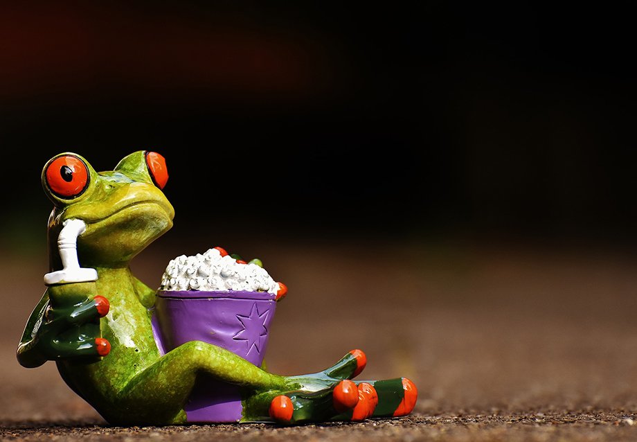 a frog figurine drinking a soda and holding popcorn