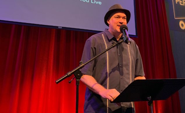 man standing on stage behind a microphone