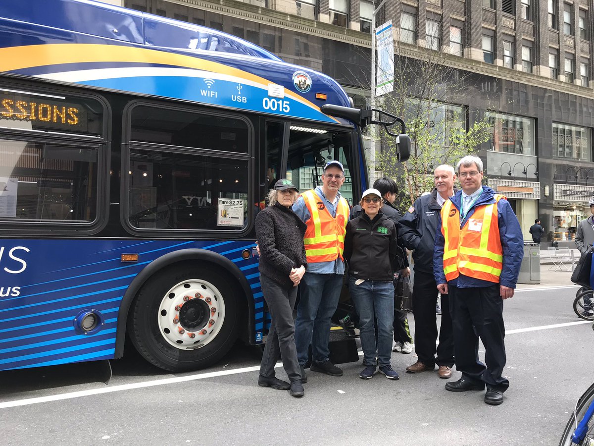 People pose for a photo next to a blue bus
