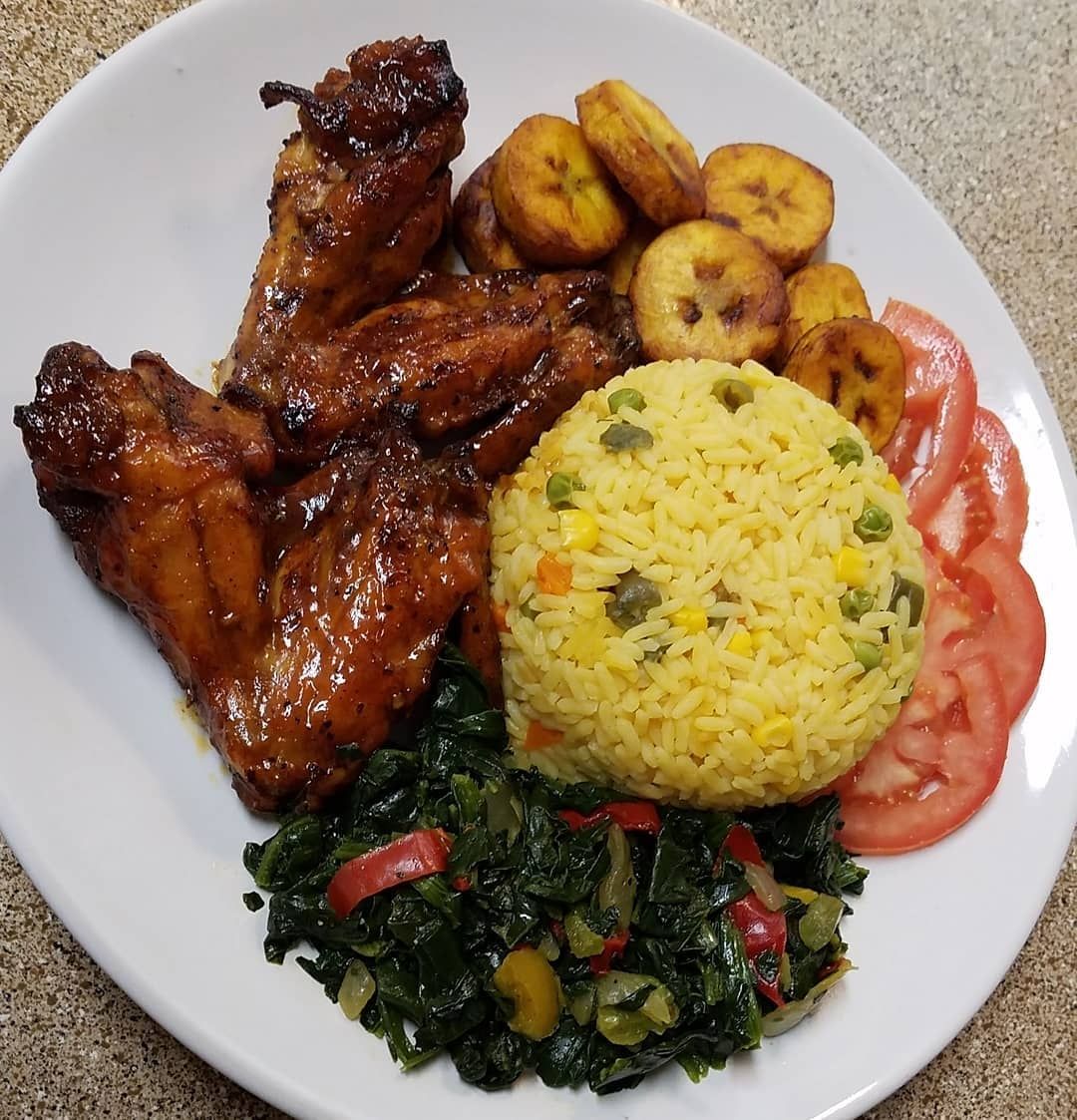 chicken wings with rice, plantains and a serving of callalloo 