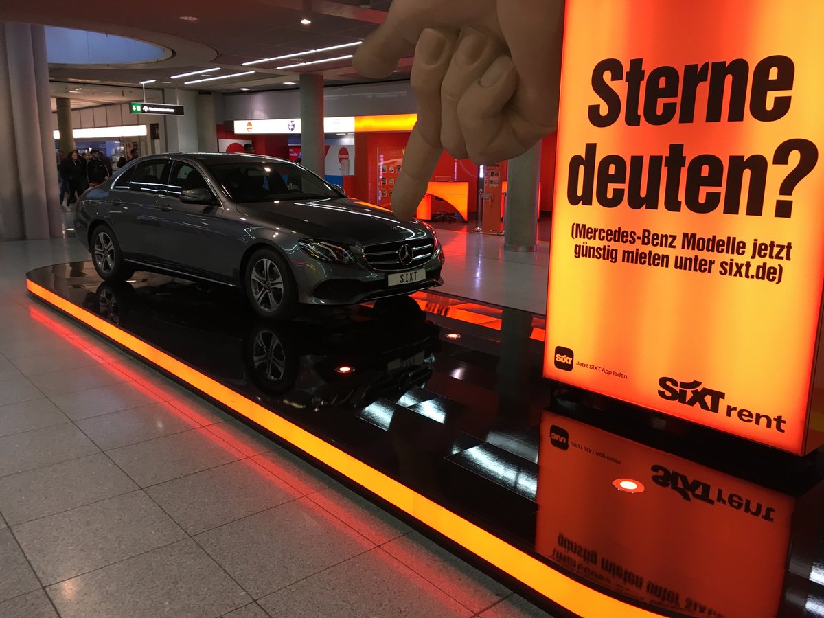 Eine große Pappmachehand, die auf den Stern eines Mercedes deutet. Daneben eine Tafel "Sterne deuten?".