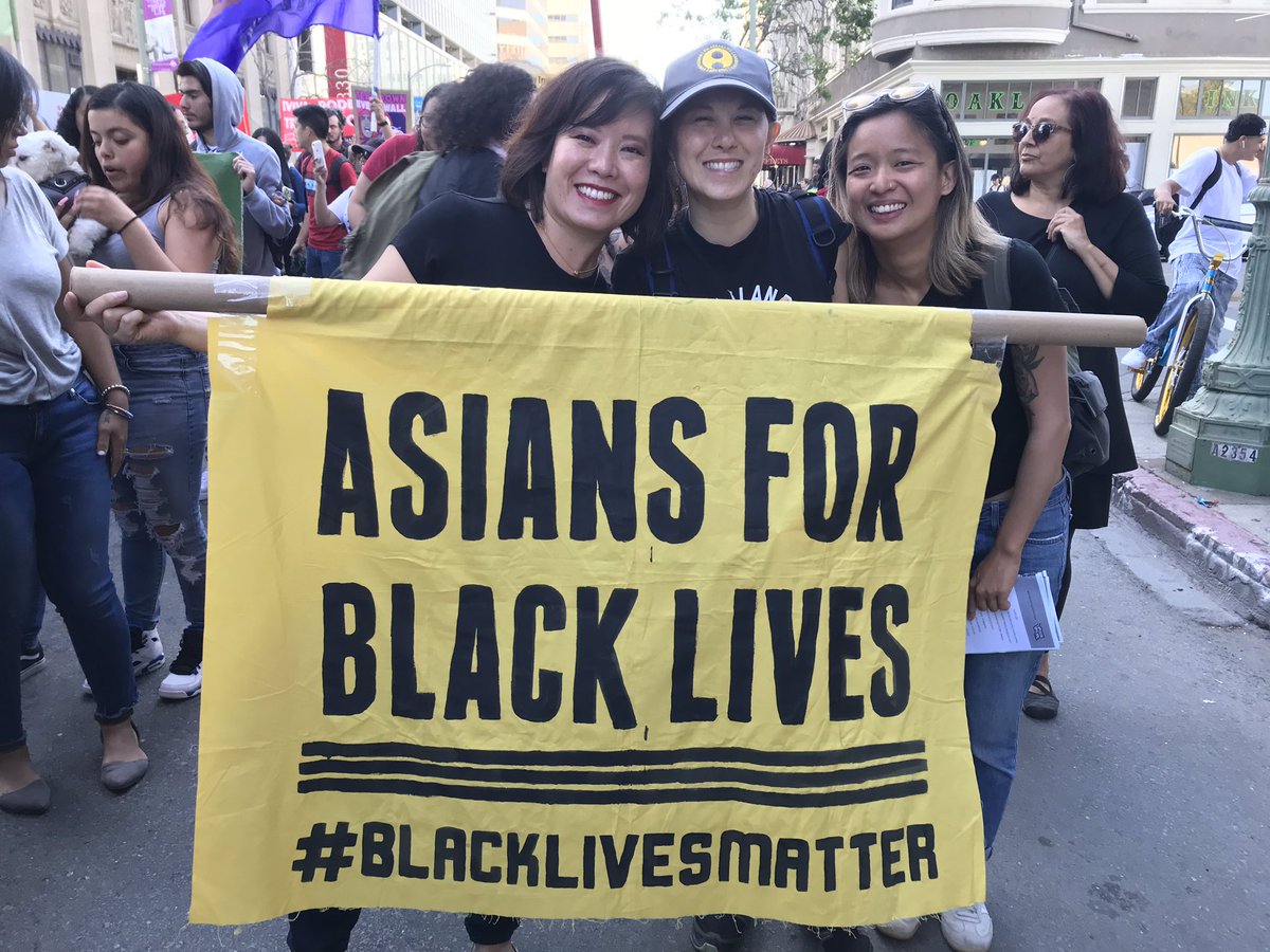 Three Asian people hold a banner that says “Asians for Black Lives #BlackLivesMatter”