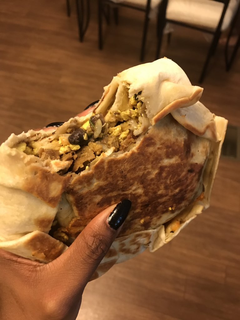 Breakfast crunch wrap with spicy potatoes. The crunch wrap has: vegan sausage, black beans, tofu scramble, tostada, 2 types of plant based cheese, lettuce, tomato and avocado 