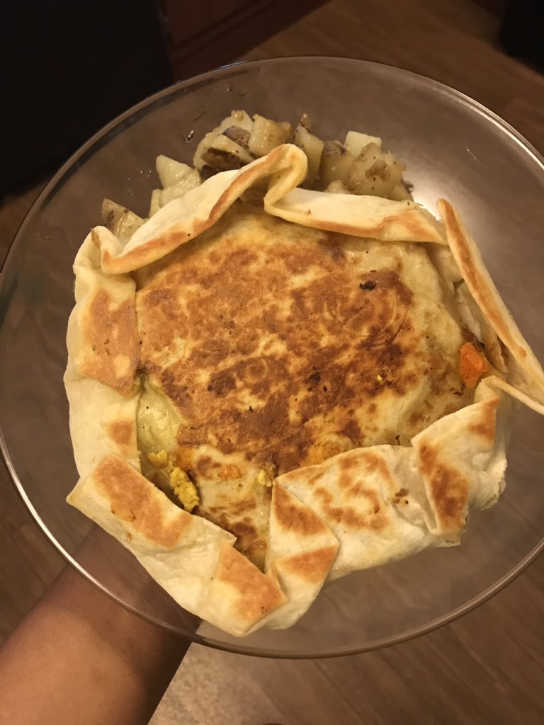 Breakfast crunch wrap with spicy potatoes. The crunch wrap has: vegan sausage, black beans, tofu scramble, tostada, 2 types of plant based cheese, lettuce, tomato and avocado 