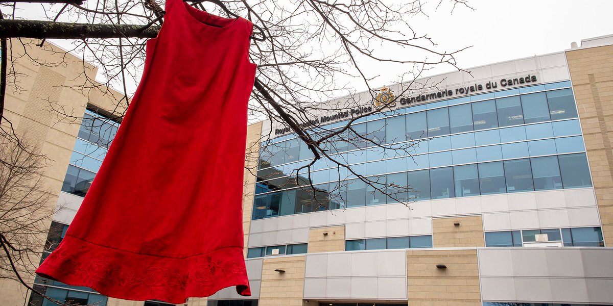A red dress hanging in a tree, in front of an RCMP building.