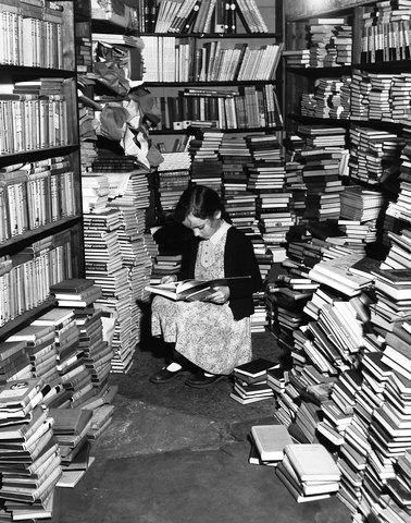 A little girl engrossed in a book in a corner of Foyles' bookshop. Soho, London, England, UK (1949)