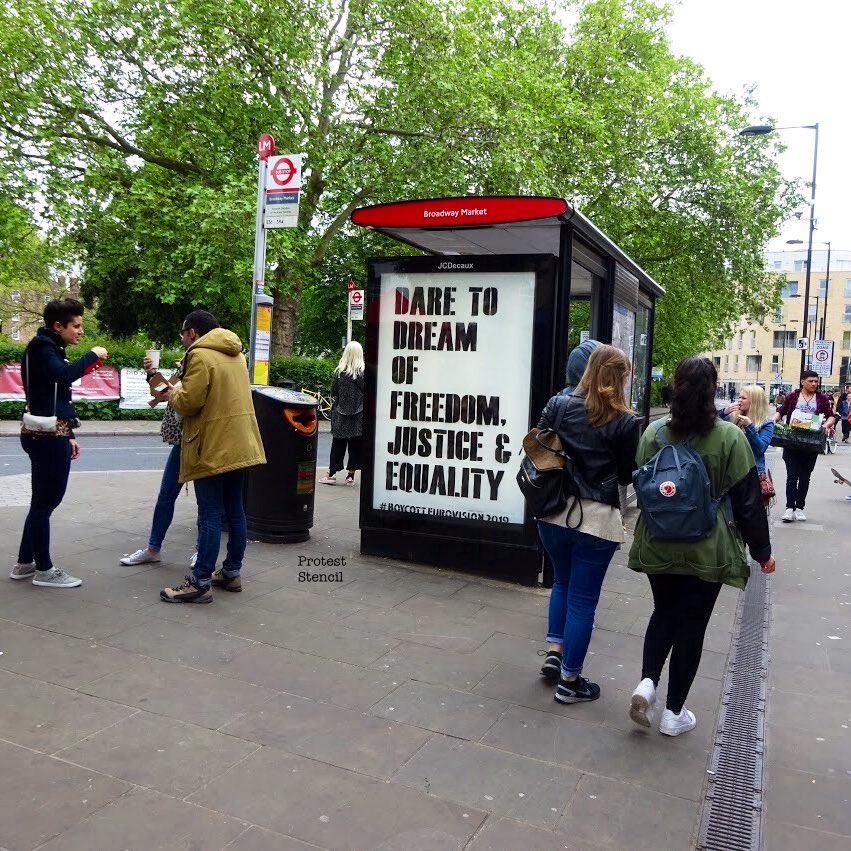 Many people around bus stop poster reading ‘Dare to Dream of freedom, justice & equality’