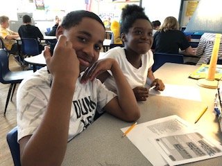 Partners working on analyzing poem " Set the Garden on Fire" (power of community gardens) - using table texting (written "conversation" done in text boxes back and forth).