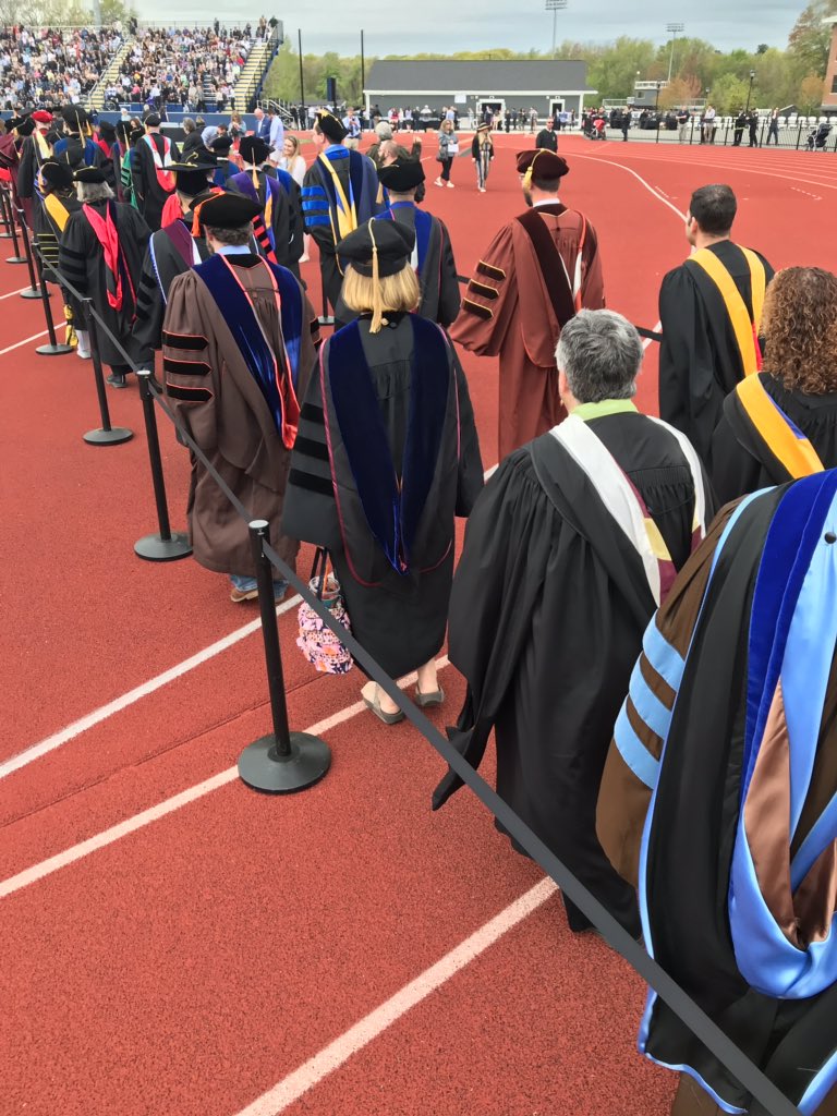 Merrimack's tweet photo. As our faculty walk into the stadium you may notice their academic regalia are different. From each cap, gown & hood, it’s possible to distinguish the institution from which the wearer graduated, the field of learning in which the degree was earned & the degree level. #MackGrad https://t.co/SN0Ps6GiOR