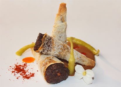 Canutillos de pan rellenos de morcilla y piñones, con crema de alubias rojas y guindillas vascas. Uno de los platos favoritos de nuestros clientes. ¡No dejes de probarlos!