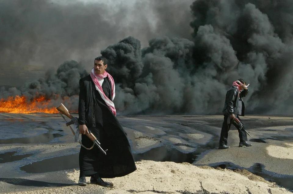 4 - Iraqi Policemen guard a sabotaged burning pipeline in Karbala. (2004)
