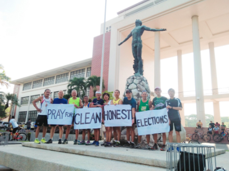 phvote's tweet photo. With only one day left before the midterm elections, 11 runners, led by "running priest" Fr Robert Reyes, posed in front of the UP Diliman's Oblation statue with a call to "pray for clean and honest elections." #PHVote | via @krishnariola https://t.co/t4N1nKbViu