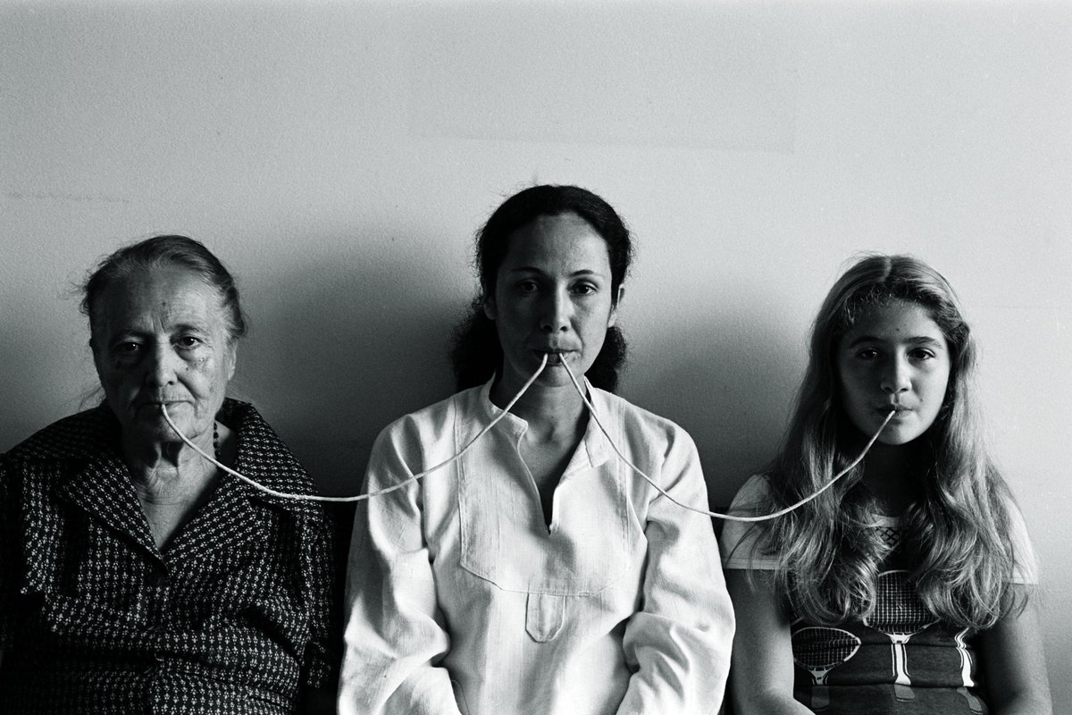 On #MothersDay we’re taking a look back at #AnnaMariaMaiolino’s photograph Por um Fio, which was featured in her retrospective at MOCA Grand in 2017. Maiolino sits between her mother and daughter, their generational connection represented by a thread held in each sitter’s mouth.